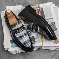 Black patent leather loafers featuring a grey plaid pattern and a gold chain detail.
