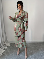 A woman wears a sage green midi dress with a floral print, long lantern sleeves, and a wrap waist.