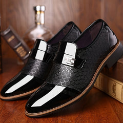 Black embossed slip-on dress shoes with a pointed toe and a metallic buckle detail.