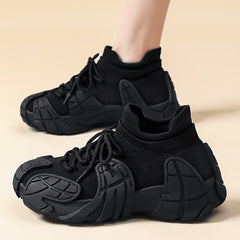A pair of black low-top sneakers with a unique textured sole and lace-up closure.