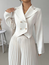 A woman wears a white double-breasted cropped blazer paired with matching pleated pants.