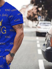 A man wears a blue short-sleeve t-shirt and matching shorts featuring an all-over King print.