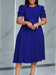 A woman wears a royal blue, short-sleeved A-line dress with a belted waist and puff sleeves.