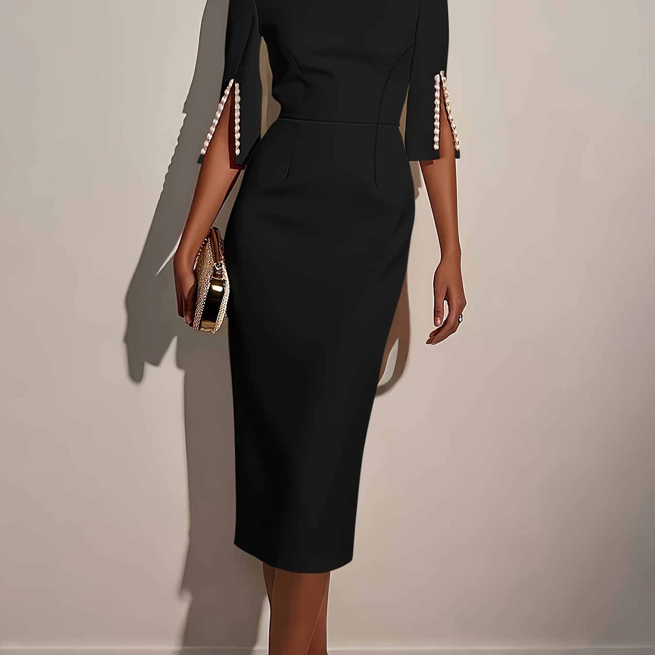 A woman wears a black knee-length pencil dress with split sleeves accented by pearl details.