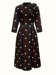 A black fit and flare midi dress featuring white polka dots, a high neck, and a side bow detail.