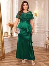 A plus-size emerald green mermaid dress featuring a sequined lace bodice and a ruffled satin skirt.
