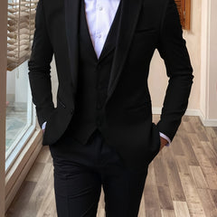 A man wearing a black three-piece suit with a shawl lapel and a white dress shirt.