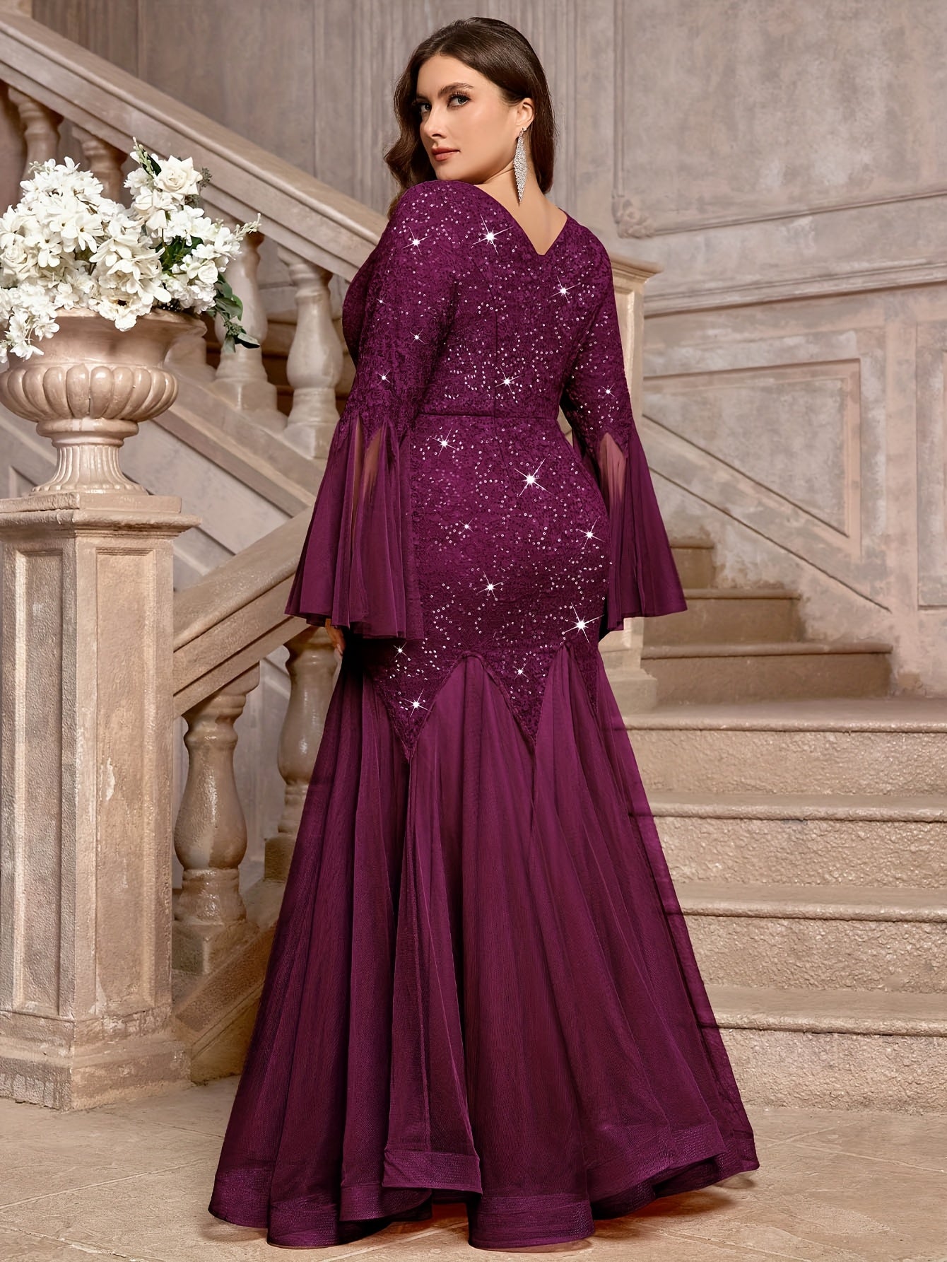 A woman wears a long, purple sequin lace mermaid gown with a V-neck and long bell sleeves.