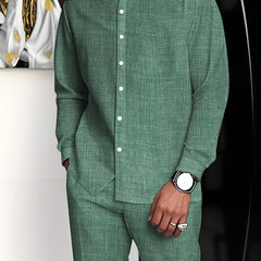 A man wears a sage green long-sleeved button-up shirt and matching straight-cut trousers.