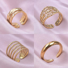 A set of four gold-toned stainless steel open rings with various textured and geometric designs.