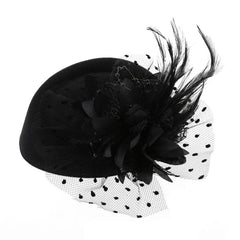 A black pillbox fascinator hat adorned with a fabric flower, feathers, and a dotted mesh veil.
