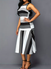 A woman wears a sleeveless, crew-neck midi dress featuring a black and white striped pattern.