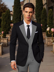 A man wears a black suit jacket over a grey vest and matching grey trousers with a white shirt.