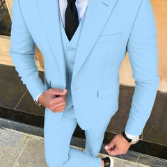 A man wears a light blue three-piece suit with a white shirt and a black tie.