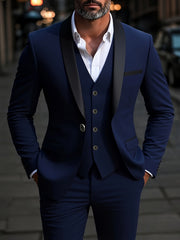 A man wears a navy blue three-piece suit with a shawl collar and a white dress shirt.
