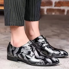 Men's pointed-toe oxford dress shoes featuring a black and white floral pattern with lace-up closures.