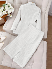 A white tweed long-sleeve jacket and matching skirt set with button details on the cuffs.