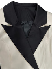 A close-up of a two-tone women's blazer featuring a black lapel against a cream-colored body.