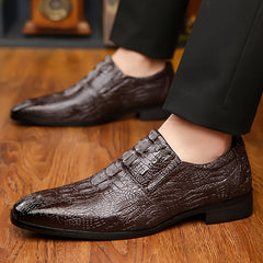 A pair of brown slip-on dress shoes with a textured crocodile-skin pattern and pointed toes.
