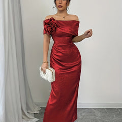 A woman wears a red off-shoulder bodycon maxi dress featuring a large floral accent and ruching.