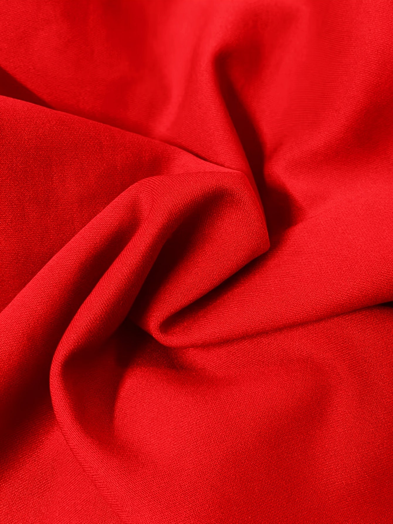 Close-up view of a vibrant red, smooth, and opaque knit fabric with soft folds.