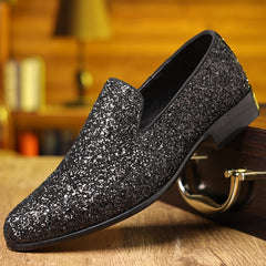 A black slip-on dress shoe with a pointed toe and a shimmering glitter finish.