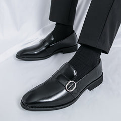 Men's glossy black pointed-toe loafers featuring a metallic buckle detail and a rubber sole.