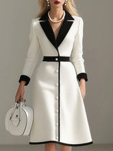 A woman wears an elegant white midi dress with black lapels, cuffs, and a button-down front.