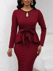 A long-sleeve burgundy midi dress with a black contrast trim, keyhole neckline, and waist tie.