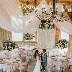Ivory chiffon ceiling drapes hanging in a decorated wedding venue.