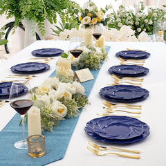 A table setting featuring blue plastic dinner and dessert plates with gold cutlery and floral decor.