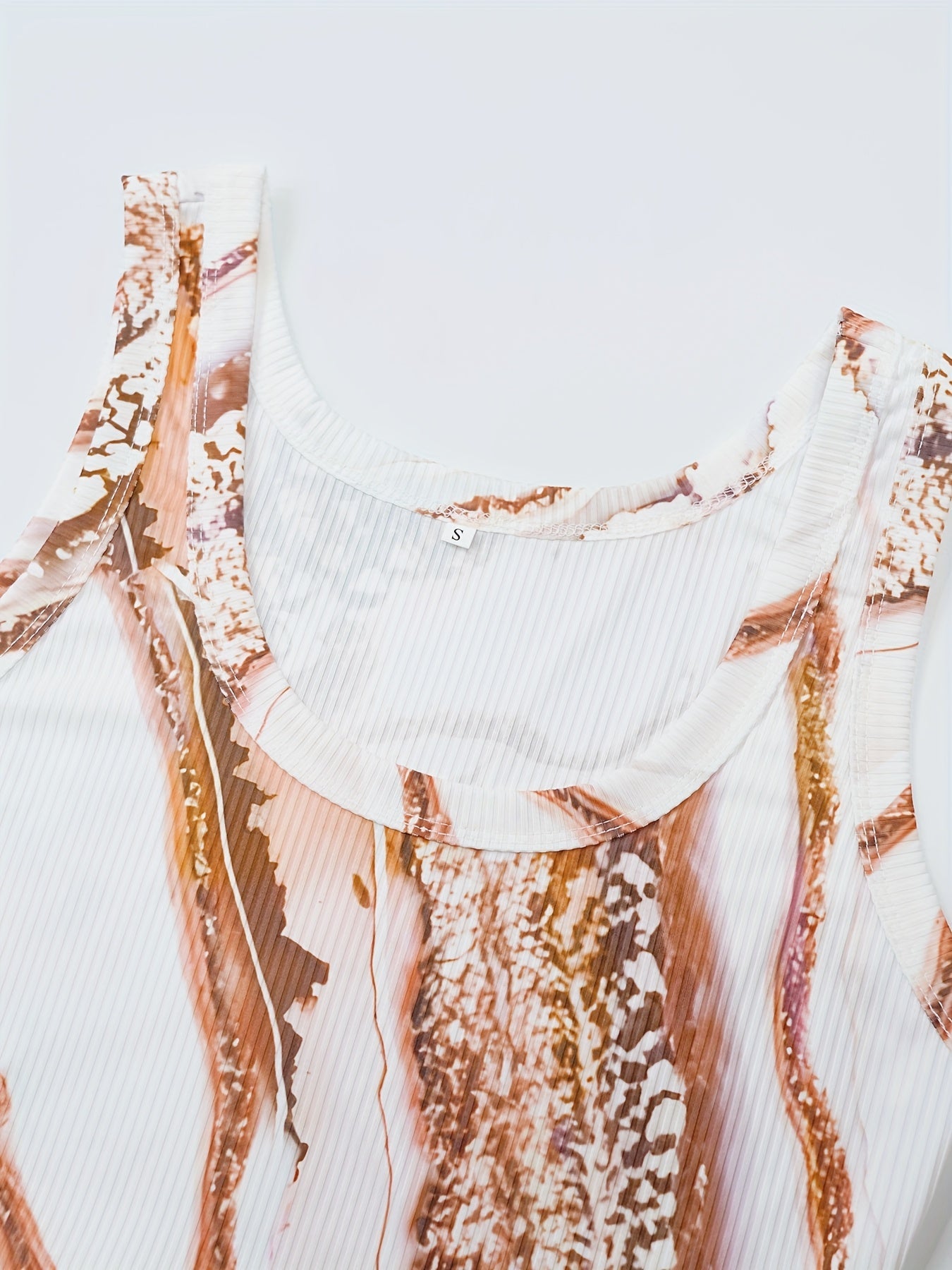 A sleeveless white ribbed tank top featuring a brown and gold abstract marble print.