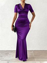 A woman wears a short-sleeved, floor-length purple bodycon dress with a cowl neckline.