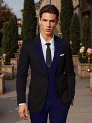 A man wears a black suit jacket with blue lapels, a blue vest, and matching blue trousers.