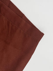 A close-up view of the hem of brown polyester trousers with visible stitching.