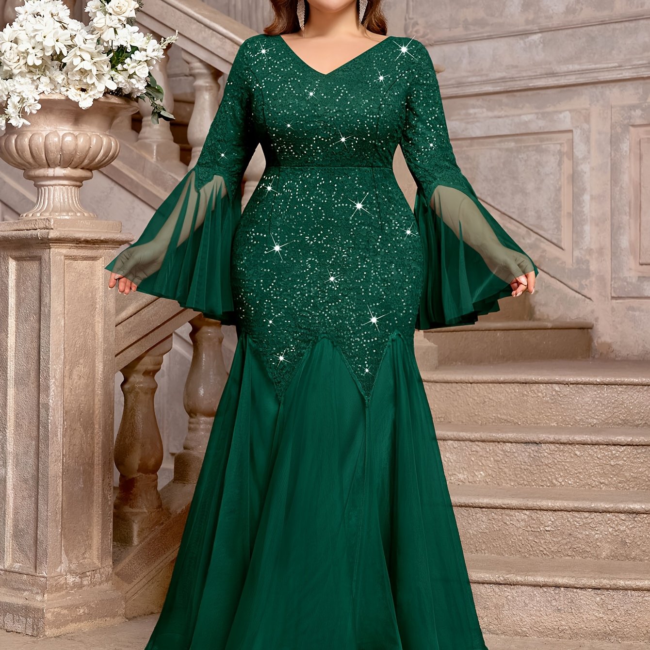 A dark green plus size mermaid gown featuring a sequined lace bodice, V-neck, and bell sleeves.