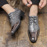 A pair of silver snakeskin-patterned men's oxford dress shoes with metallic toe caps and black laces.