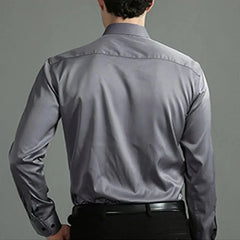 A man seen from behind wearing a long-sleeved, solid grey button-down business casual shirt.