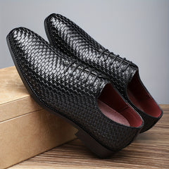 A pair of black woven lace-up Oxford shoes with a red interior and rubber soles.