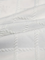 Close-up of a white t-shirt featuring a textured geometric jacquard knit pattern.