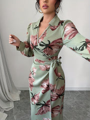 A woman wears a sage green midi dress with a floral print, V-neckline, and a side tie waist.