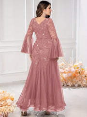 A dusty rose sequin lace gown featuring a V-neck, long bell sleeves, and a mermaid tulle hem.
