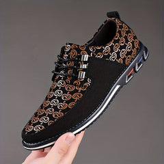 A hand holds a black and brown geometric patterned lace-up casual shoe with a white rubber sole.