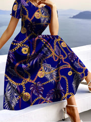 A woman wears a vibrant blue A-line dress featuring a gold chain and tropical palm leaf print.