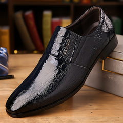 A sleek black men's slip-on loafer with a pointed toe and a glossy crocodile skin texture.
