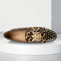 A leopard print loafer with gold spikes on the toe and a decorative gold emblem on the vamp.