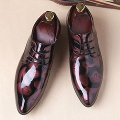 A pair of men's pointed-toe faux leather oxford dress shoes featuring a dark floral pattern.
