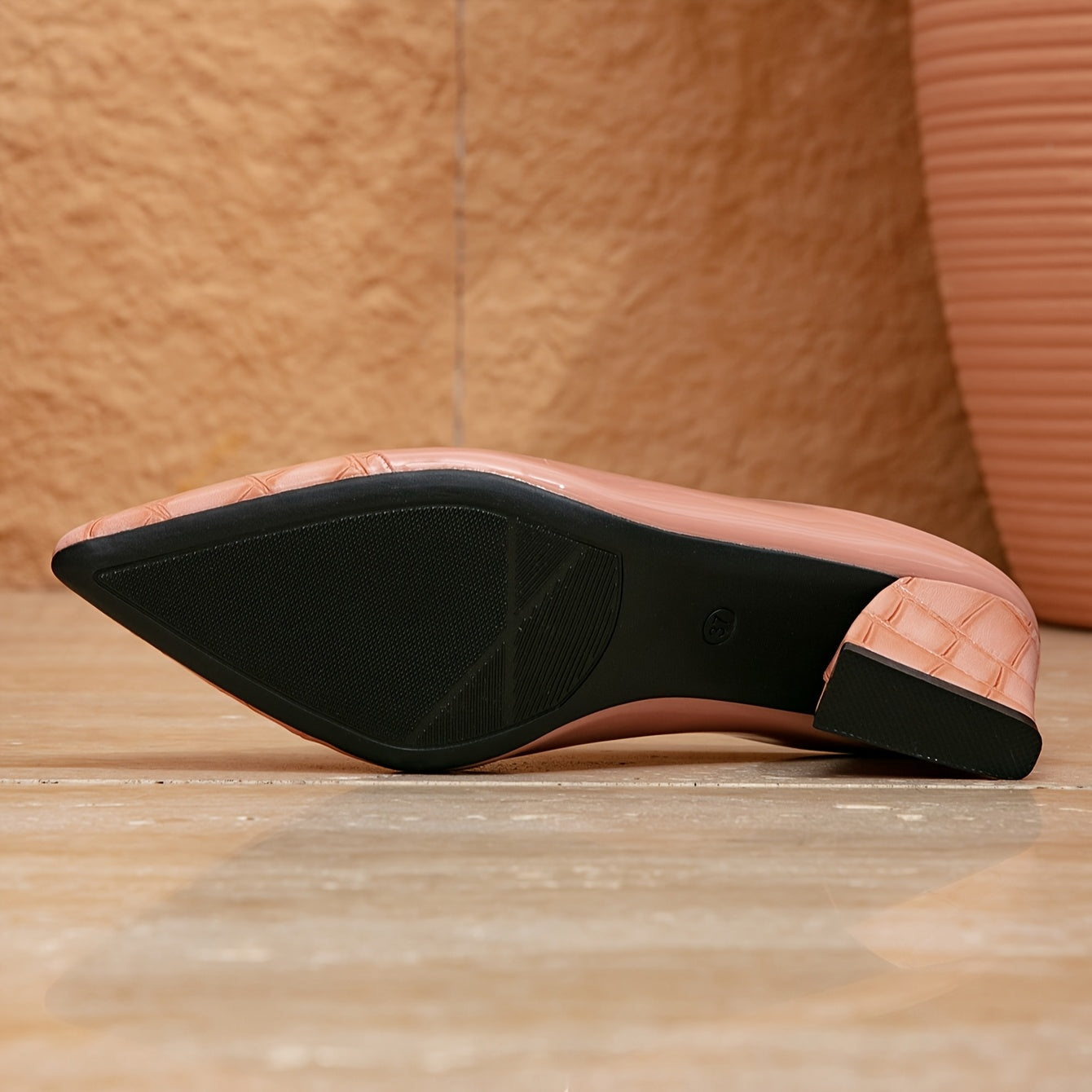 A pink pointed-toe mule with a chunky block heel and a textured finish, shown from the sole.