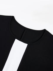 A close-up view of the black crew neck on a two-tone dress with a white vertical panel.