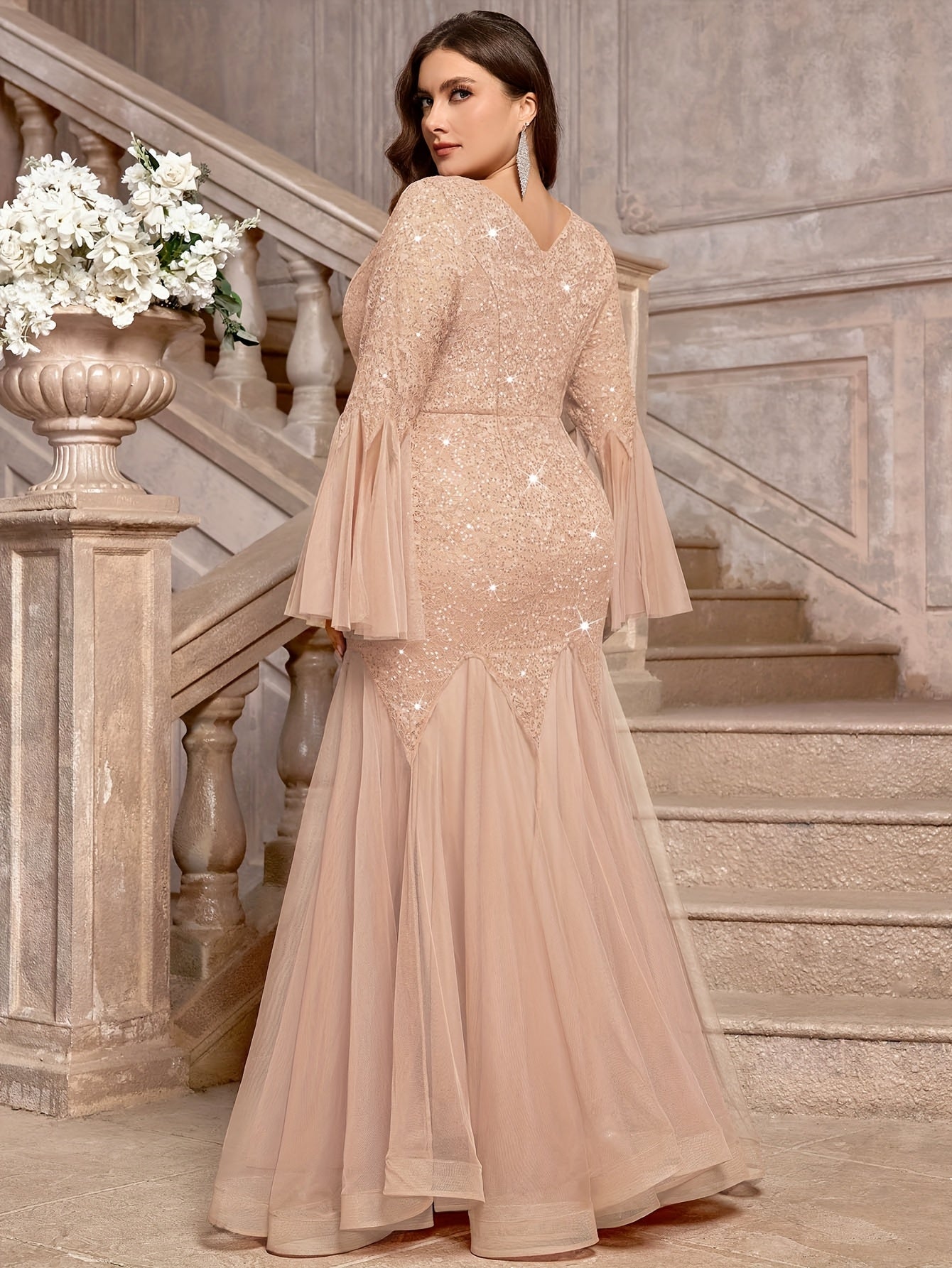 A plus size champagne sequin lace gown with a V-neck, bell sleeves, and a mermaid tulle hem.